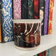 Locked Tomb ceramic mug with skeleton design on a bookshelf with patterned books