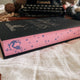 Mortal Follies by Alexis Hall digitally sprayed pink edges, with a purple bird at the bottom of the long edge.