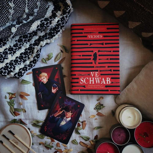 Vicious red hardback laid on a badsheet with some candles and postcards of Victor and Eli image